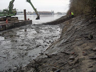 Work in progress at the waterside of the Holzhafen: an excavator removes the last rocks from the bank