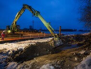Work in progress at the waterside of the Holzhafen: an excavator removes rocks from the bank revetment in the evening