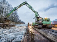 Work in progress at the waterside of the Holzhafen: an excavator removes rocks from the bank revetment