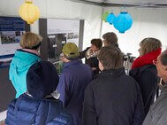 In a tent, Dr. Elisabeth Klocke explains the process of the project to an audience